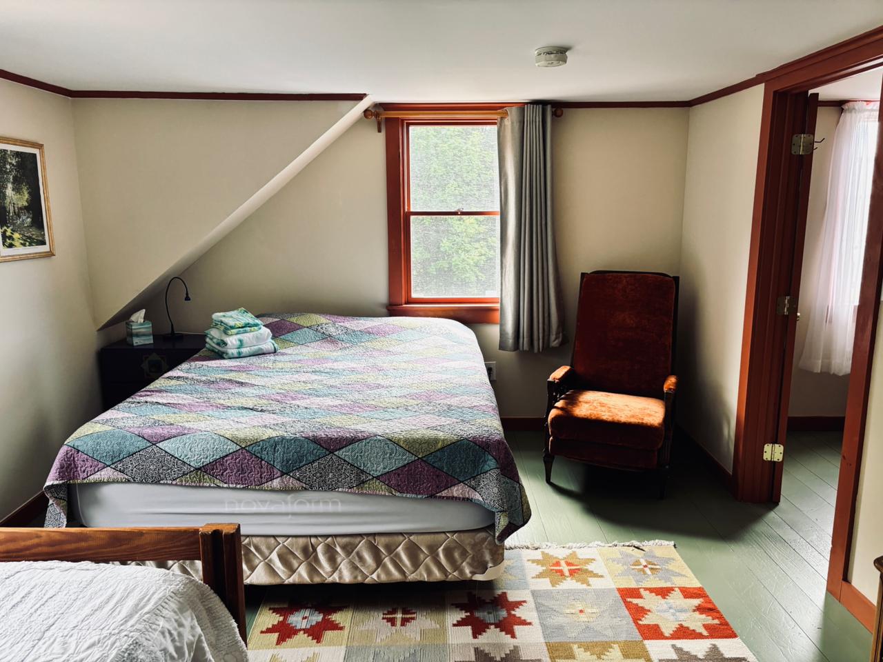 Queen bed with patchwork quilt and sloped ceiling