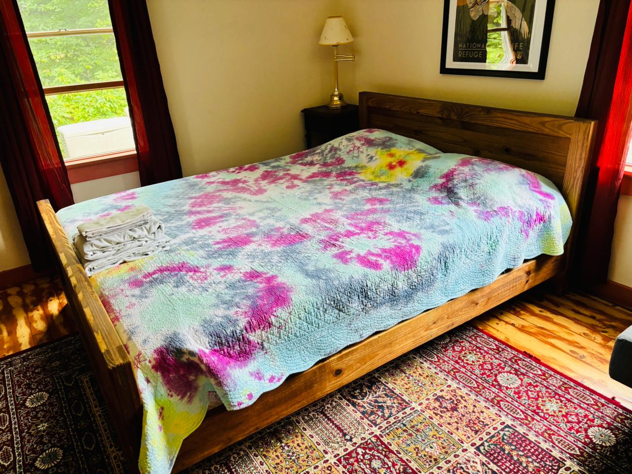 Pink tie-dye quilt on rustic wooden bed
