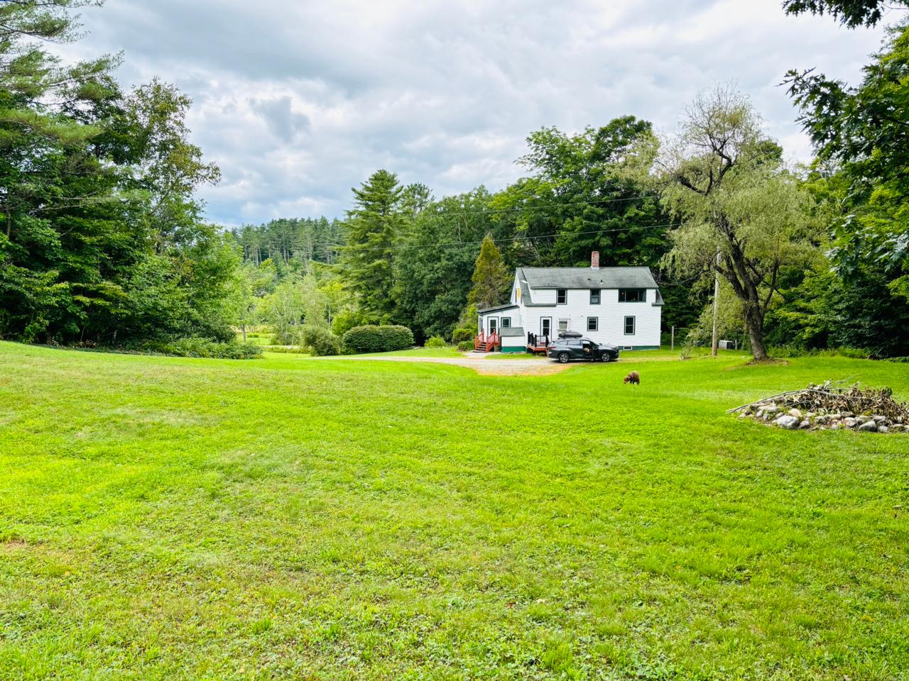 White farmhouse with chimney and large yard